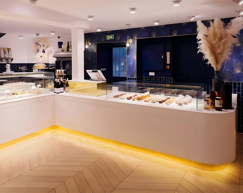 ONI-Shopfitting Curved White Display Counter for Bakery with Warm Lighting and Luxury Accents